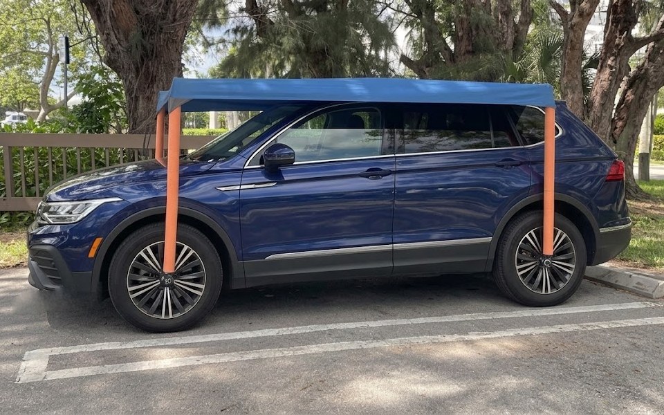 Side view of a navy SUV under the UVgotshade canopy, a pole rising from each wheel hub and nothing touching the pavement